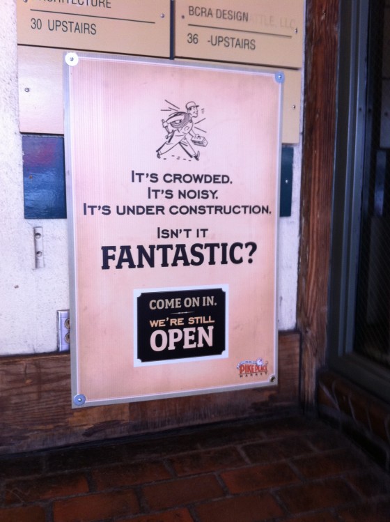 Picture of sign in Seattle's public market that reads, "It's crowded, it's noisy, it's under construction. Isn't it FANTASTIC?"